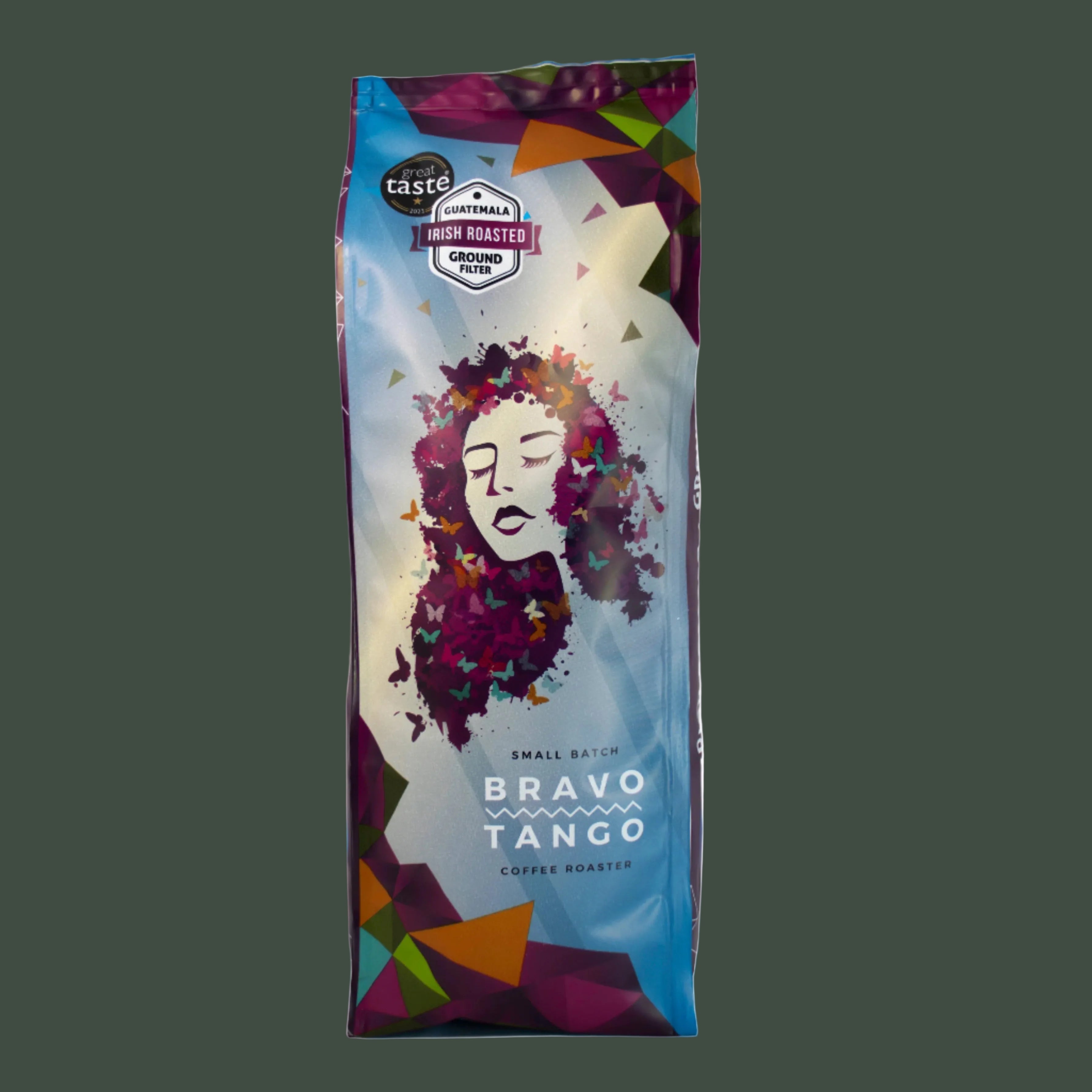 A bag of Taste Australia Bravo Tango Coffe Roast, featuring a colorful graphic of a woman's face made of flowers on a blue and white background, set against a dark gray backdrop.