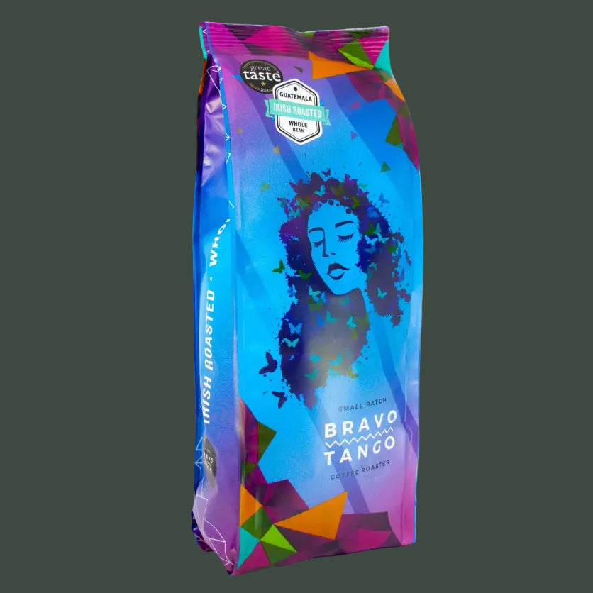 A bag of coffee labeled 'Bravo Tango' with a colorful geometric design in blue, purple, pink, green, and orange, shown on a dark gray background.