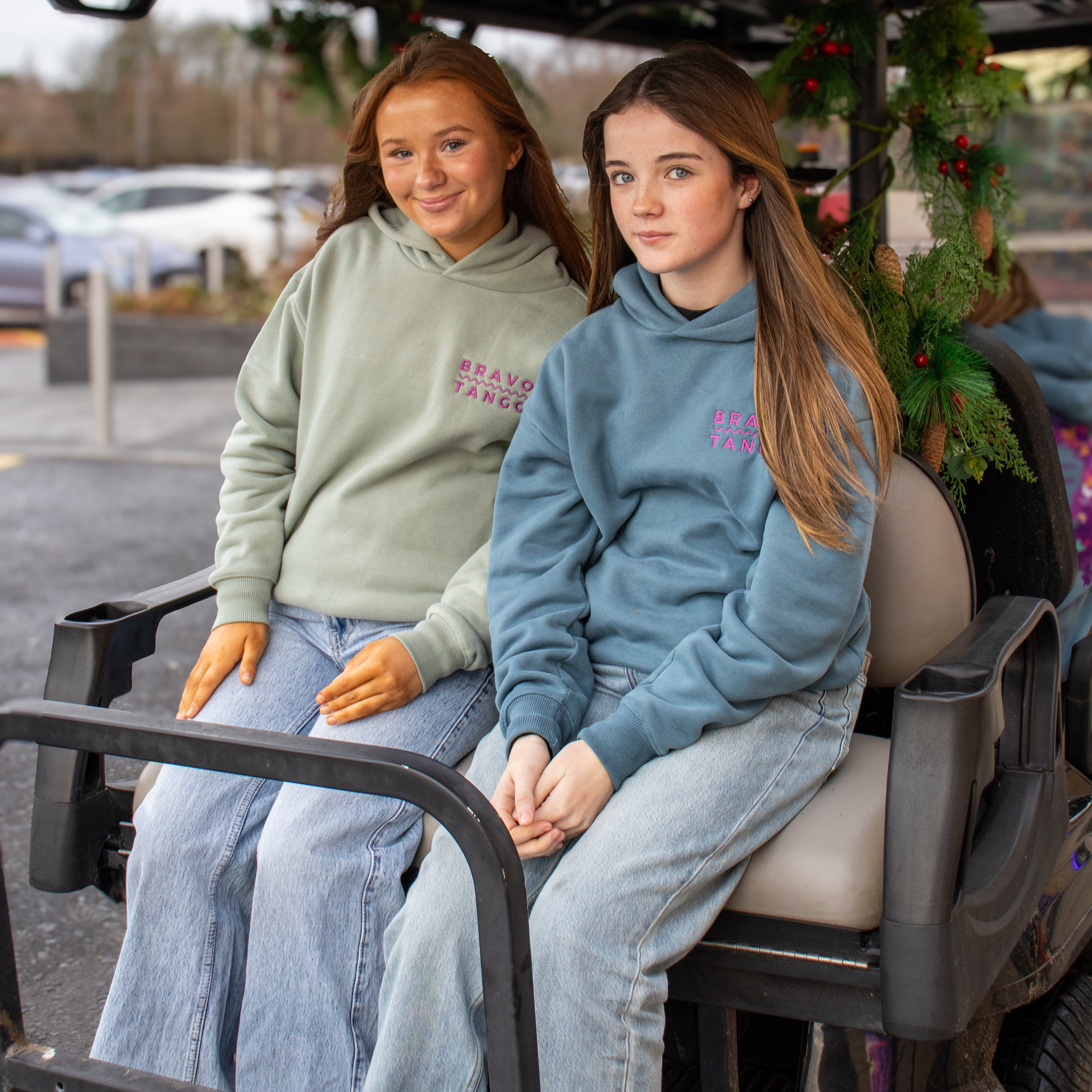Two women sitting in a golf cart with a festive background
